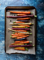 Roasted rainbow carrots on a parchment lined baking sheet.