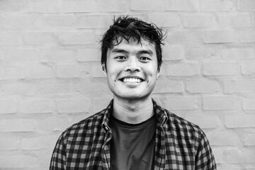 Happy Asian guy portrait - Confident asian young male having fun smiling while posing in front of camera - Black and white