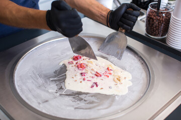 Stir-fried ice cream rolls at freeze pan. Rolled ice cream, hand made ice cream dessert. Fried ice cream machine with steel chilled pan.