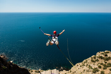Rope jumping off a cliff with a rope in the water. The ocean. Sea. Mountain