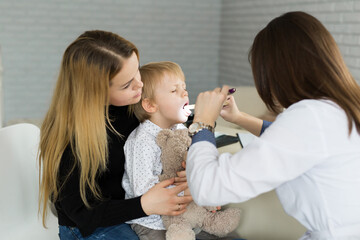 Doctor examine child's throat. Boy and mother at pediatrician office.