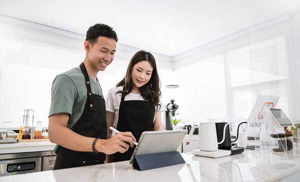 Startup successful small business owner sme boy girl stand with tablet in coffee shop restaurant. Portrait of asian tan man woman barista cafe owner. SME entrepreneur seller business delivery concept
