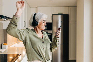 Happy senior woman dancing to her favourite music at home