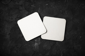 Photo of two blank white beer coasters on black stone background. Responsive design mockup. Flat...