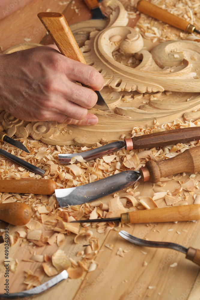 Wall mural woodworker's workbench. closeup man's hand. a man working with woodcarving instruments.