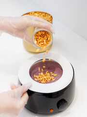Violet hot liquid wax for depilation on a wooden stick. The concept of depilation, beauty, skin care. Wax melting device. Web banner