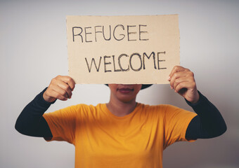 Woman holding pieces of paper with words Refugee Welcome message for help people concept NO WAR...