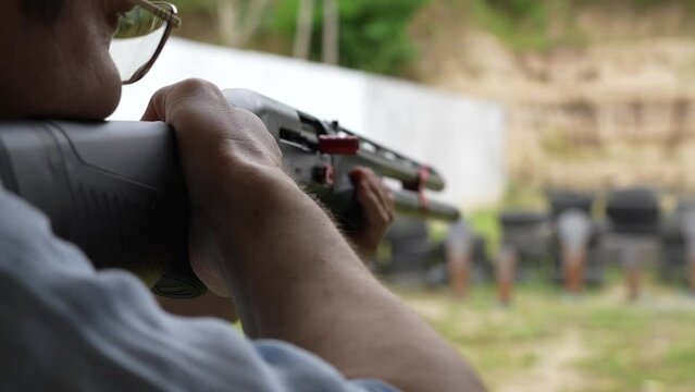 Man shoots with a combat shotgun at targets on the shooting range, close up, slow motion. Back view of man shooting shotgun at target while practicing