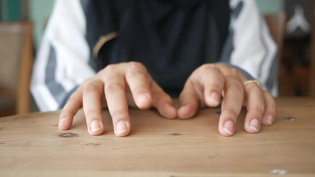 a nervous young women hand on table 