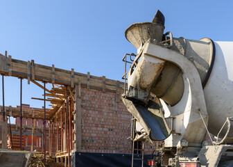 Concrete mixer at the construction site. The process of pouring concrete. Brick house under...