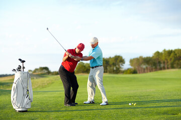 Obraz premium The correct technique. A male golfer getting help from his caddy on the golf course.