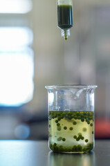 green bead in lab beaker and syringe