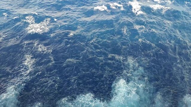 Tilt shot from a cruiser. First water by the side agitated by the propulsion and then view of the open sea and horizon on a birght but cloudy day.
