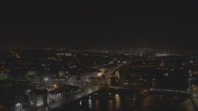 Pulling out, this drone shot gives full view of Galway, Ireland at night. The beautiful city lights create an inviting atmosphere. The city lights in the horizon give this shot great depth.