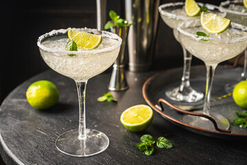 Margarita cocktail with lime and ice on dark wooden table with copy space. Classic Margarita and Daiquiri Cocktail.