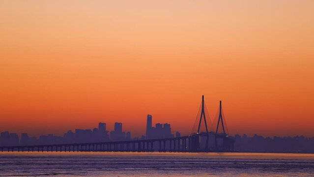 scenery of a huge bridge before the sun comes out from the horizon. You can also see lights of cars on the bridge.