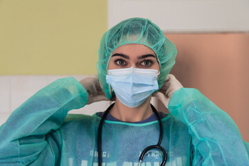 The female animal surgeon or veterinarian puts on a medical face mask. Doctor is preparing for surgery in the operation room. Medicine and healthcare