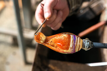 Glass blowing The hands of the craftsman working with molten glass Traditional crafts