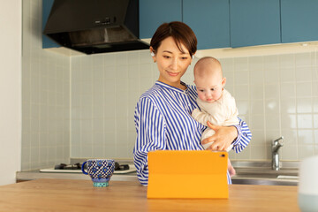 Mother holding baby girl using digital tablet