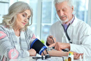 Fototapeta premium Portrait of elderly doctor measuring blood pressure
