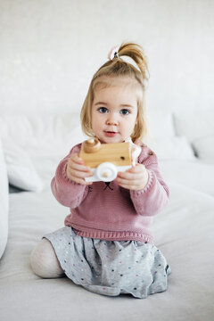 Small adorable girl holding wooden toy camera 