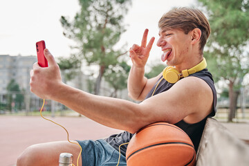 basketball player resting. male athlete sitting while making a video call on his mobile phone.