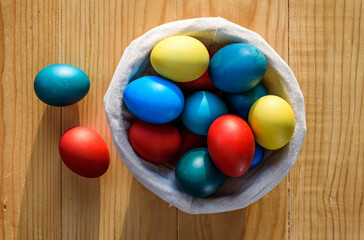 Fototapeta na wymiar Colorful easter eggs in a wicker basket on a wooden table. Top View