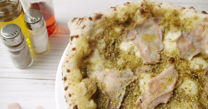 Pizza with Meat, Pesto, Cheese and Parmesan fresh out of the oven ready to eat. Delicious Italian pizza. Napoli Pizza. Food Service on white table and ingredient. Tasty Pizza with Cheese and Parmesan.