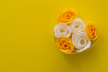 Gift box of soap in the form of white and yellow roses on a yellow background. Top view, space for text, copy space