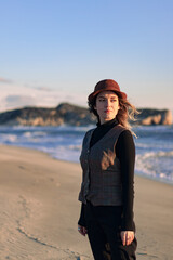 Fall fashion. Beautiful woman in brown hat, dress in nature portrait. Sunlights. Amazing sea and mountain background.