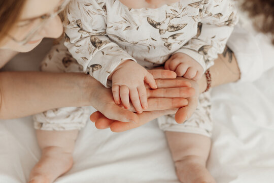 Top view of young loving family stacking hands. Father, mother and cute little baby holding palms together sitting.