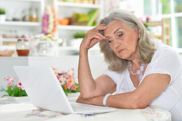 Portrait of tired senior woman using laptop