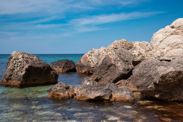 Fototapeta na wymiar Summer seascape. Rocks and stones near the coastline. Blue sky and ocean.
