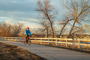 senior male cyclist is riding a gravel bike on one of numerous bike trails in northern Colorado in fall or winter scenery - Poudre River Trail near Windsor