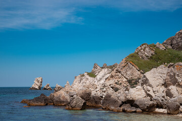 Fototapeta na wymiar Summer seascape. Rocks and stones near the coastline. Blue sky and ocean.
