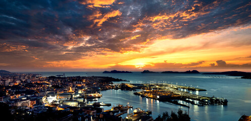 Vista general de Vigo al atardecer con la ciudad y el puerto y las Islas Cíes al fondo, con un...
