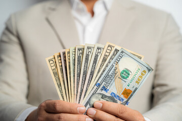 Business man and money in us dollar hold on hand wearing a brown suit jacket and Give to me USD, Pay, exchange money on white background. Business finance and bank employee Concept.