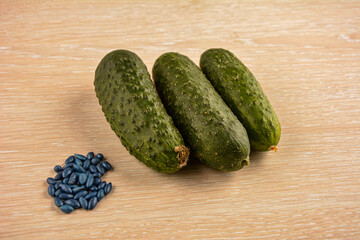 Green cucumbers lie on the table and hybrid seeds next to them.
