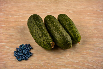 Green cucumbers lie on the table and hybrid seeds next to them.