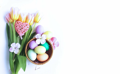 Easter flower arrangement - pink tulips, multicolored eggs in wicker baskets on a white background. Background for a greeting card. 