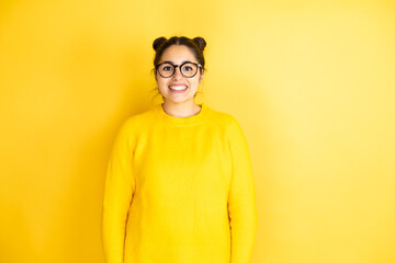Fototapeta premium Young beautiful woman wearing casual sweater over isolated yellow background with a happy face standing and smiling with a confident smile showing teeth