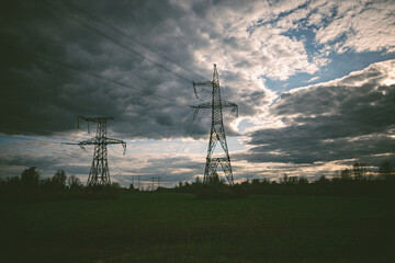 Big electricity high voltage pylons with power lines on a field in a foggy morning. Sustainable...
