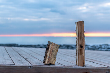 Fototapeta premium Two piecves of firewood (split) sit on a dock with the dawn sky behind them. Shot in the Toronto's Beaches neighbourhood. Room for text.
