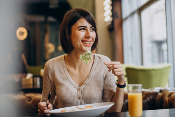 Young woman eating healthy breakfast with juice in a cafe