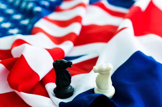 Two knight chess pieces standing on american and french flags