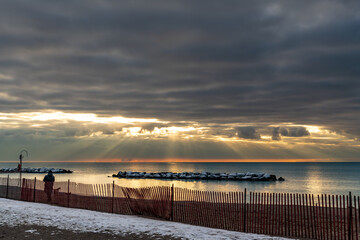 Obraz premium A woman and her dog walk on an empty beach just after dawn on a March morning in Toronto's Beaches neighbourhood. Room for text.