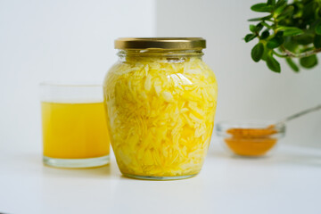 Fermented cabbage with turmeric. Cabbage kvass. Pickling vegetables without salt. Fermentation. Vitamin treatment and nutrition. Organic turmeric powder and green leaves of houseplant in a frame.