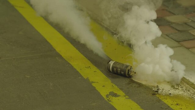 Throw of Military smoke bomb on the street . Throwing of smoke grenade . Pulling smoke grenade . Military or police theme concept . Shot on ARRI cinema camera in slow motion .