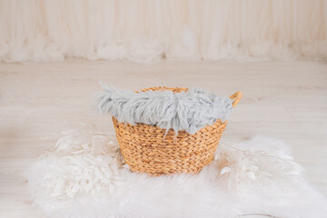 A basket for a newborn baby with white flowers in a photo studio