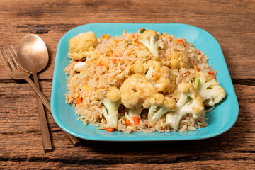 Fried rice with vegetable and egg in plate on wood background.